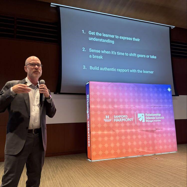 A speaker with a microphone presents a slide on building authentic rapport with learners