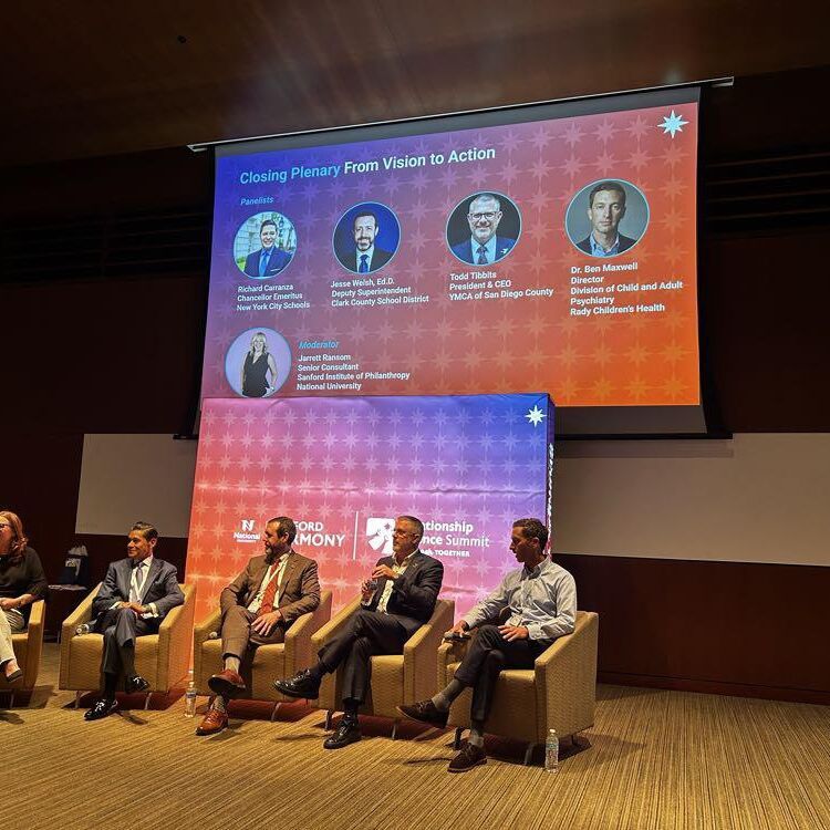 Panelists seated on stage during the closing plenary, From Vision to Action