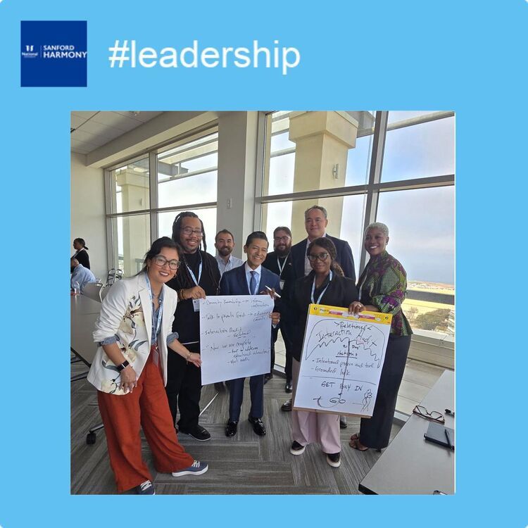 Summit participants gather around flip charts during a leadership working session
